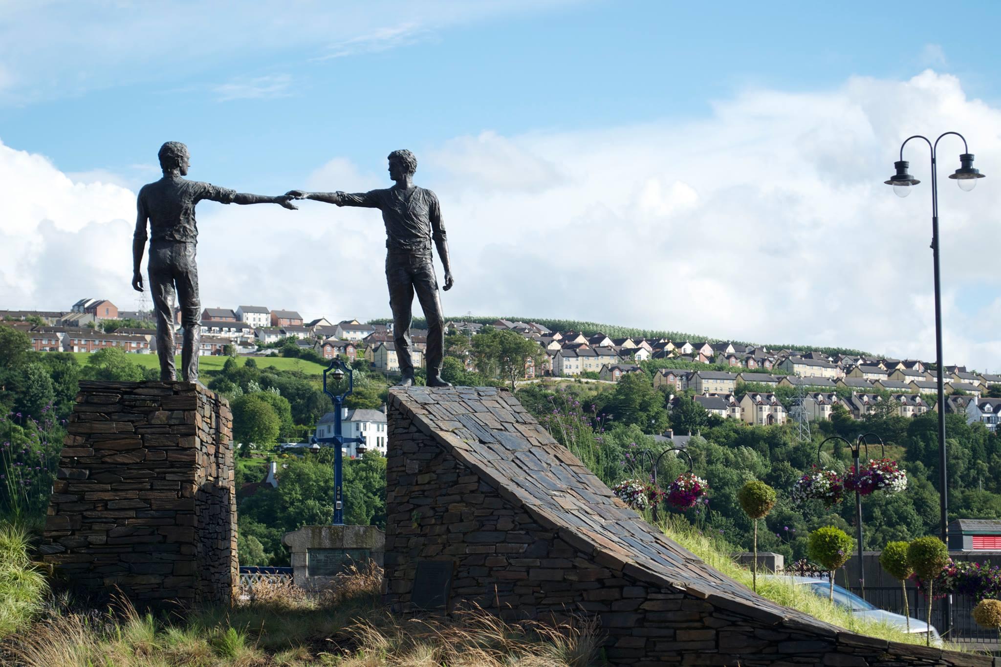 Two statues of people nearly touching hands